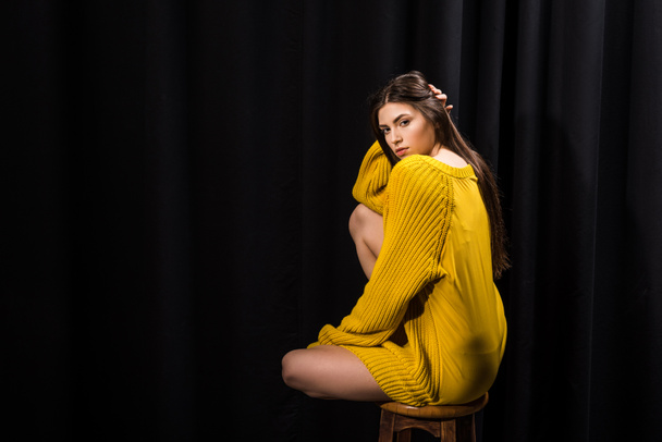 young attractive woman in yellow woolen sweater on black backdrop - Фото, изображение