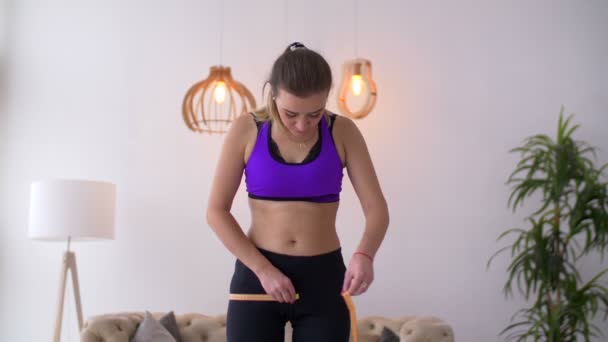 Slim woman measuring her hips with measuring tape - Felvétel, videó