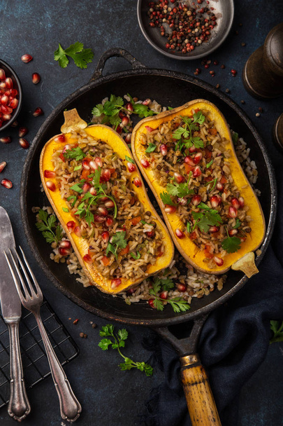 butternut squash stuffed with brown rice and vegetables, served with pomegranate and coriander, top view - Fotó, kép