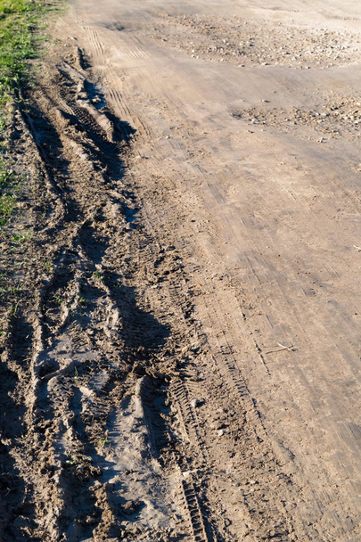 Neumáticos profundos en el camino cubiertos de arena mojada y fangosa
 - Foto, Imagen