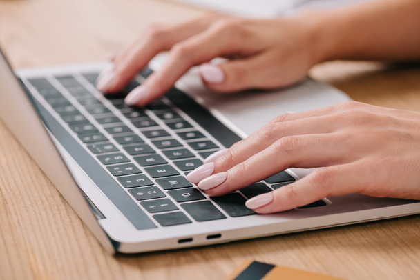 vista parcial de la mujer escribiendo en el ordenador portátil en la mesa con tarjeta de crédito
 - Foto, imagen
