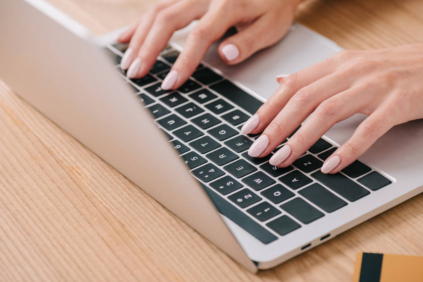 vista parcial de la mujer escribiendo en el ordenador portátil en la mesa con tarjeta de crédito
 - Foto, imagen