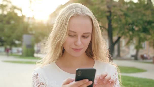Mladá blondýnka dáma pomocí telefonu ve městě - Záběry, video