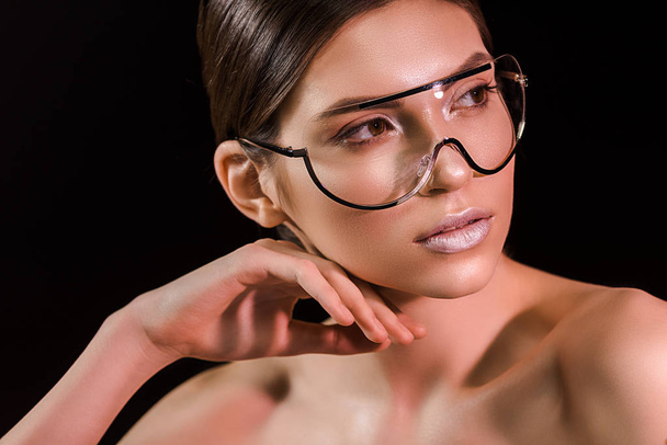 portrait of attractive young woman in fashionable eyeglasses with bare shoulders isolated on black - Photo, Image