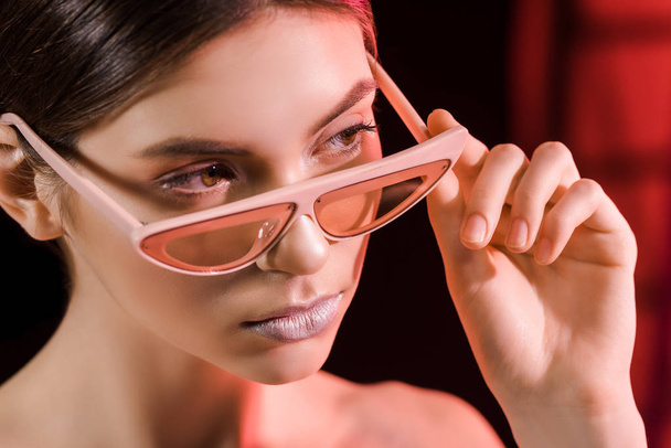 portrait of stylish model in eyeglasses posing on dark background - Foto, afbeelding