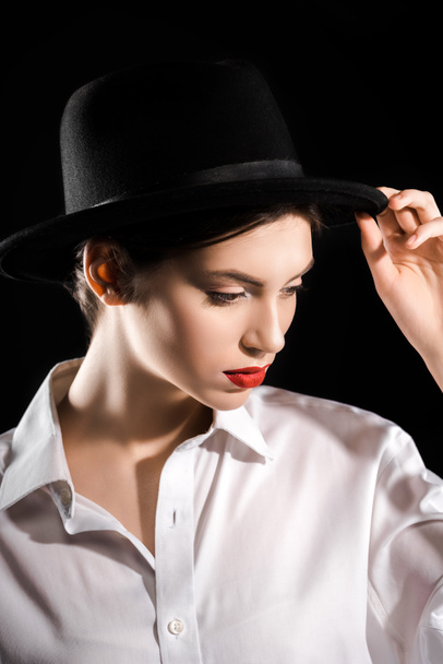 portrait of stylish woman in black hat and white shirt posing isolated on black - Foto, afbeelding
