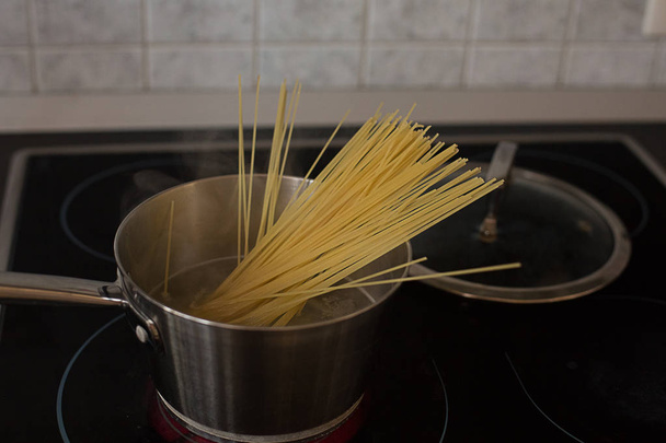 spaghetti Italian pasta is cooked in a pot on an electric stov - Foto, Imagem