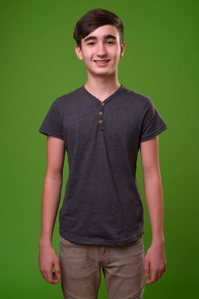 Young handsome Iranian teenage boy against green background - Photo, Image