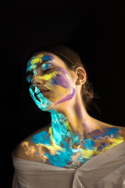 woman with ultraviolet paints on face posing on black background - Valokuva, kuva