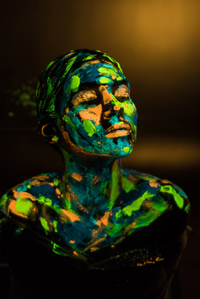 portrait of woman painted with bright neon paints on dark backdrop - Zdjęcie, obraz