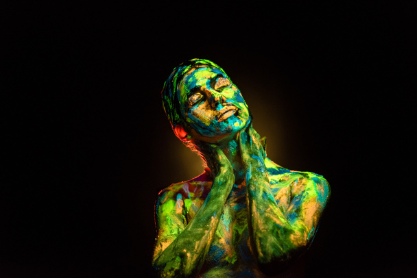 portrait of beautiful woman with colorful ultraviolet paints on body on black backdrop - Photo, Image