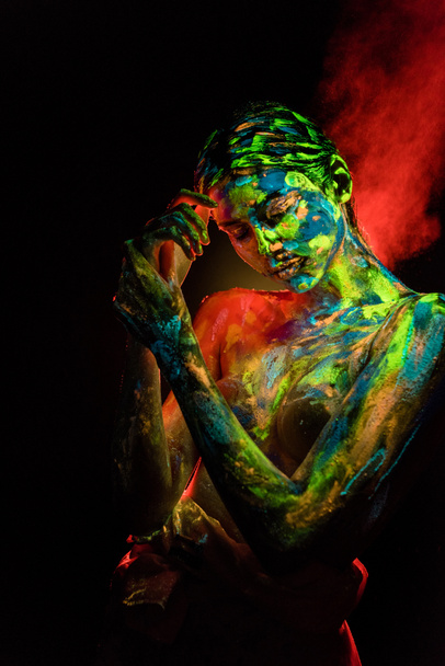 portrait of beautiful woman with colorful ultraviolet paints on body on black backdrop - Foto, imagen