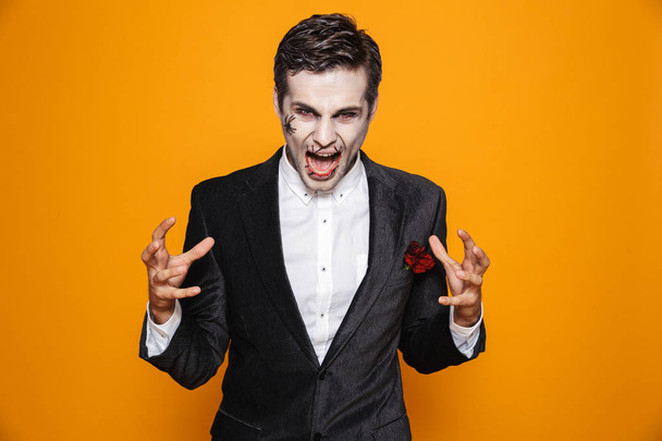 Angry psycho man zombie in suit screaming and looking camera isolated over orange - Foto, imagen