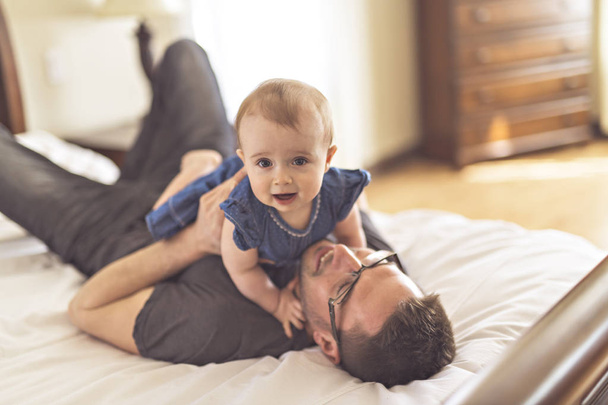 Father playing with her baby in the bedroom - Foto, afbeelding
