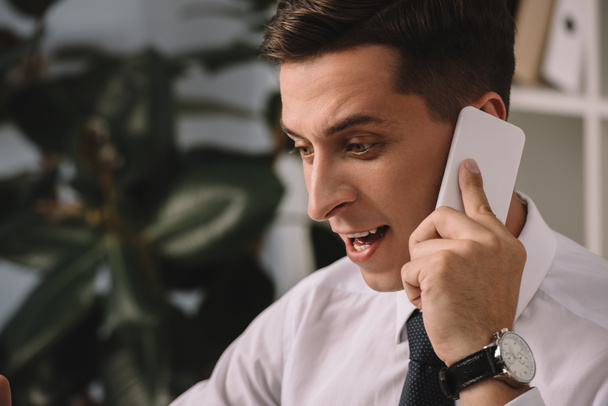 emotional businessman having conversation on smartphone in office - 写真・画像