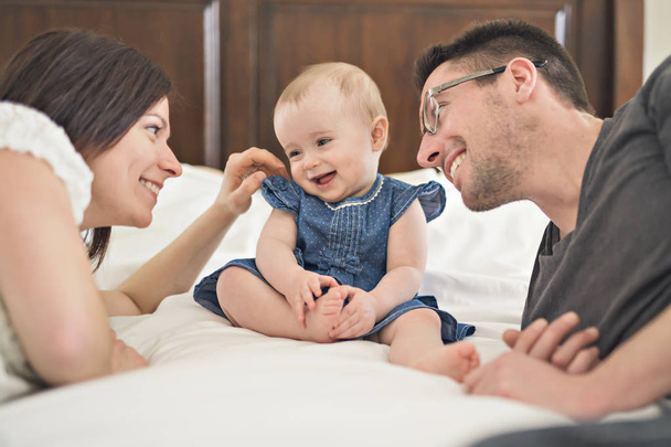 счастливая семья мать, отец и ребенок дома в постели
 - Фото, изображение