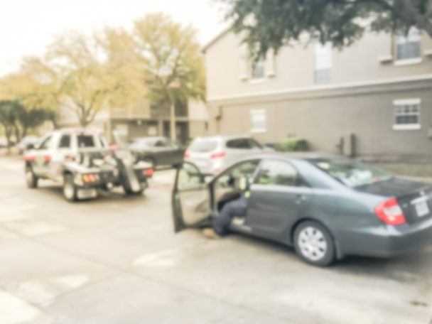 Κίνηση θολή χονδρό οδηγός φορτηγού ρυμούλκησης ένα κατεστραμμένο αυτοκίνητο από διαμέρισμα κτιριακό συγκρότημα στο Τέξας, Αμερική. Ασφάλιση θεματικού concept, οδική βοήθεια ατυχήματος υποστήριξη - Φωτογραφία, εικόνα