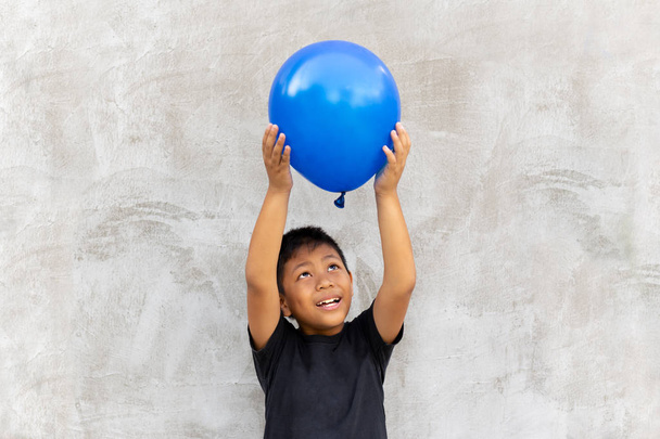 Asian boy play catches balloon on grey background - Foto, Imagen