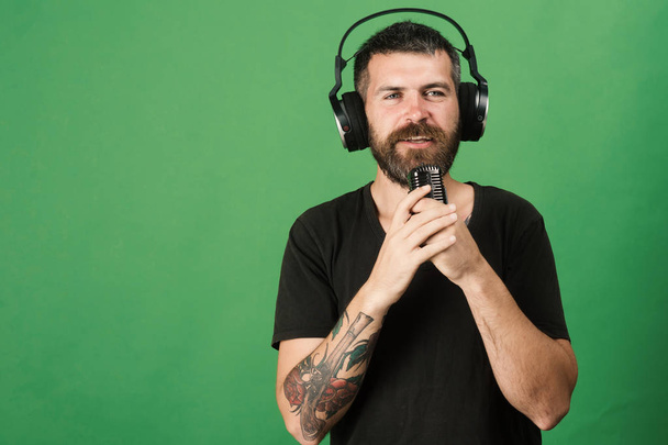 Dj with beard wears headphones, copy space. Man holds microphone - Photo, Image