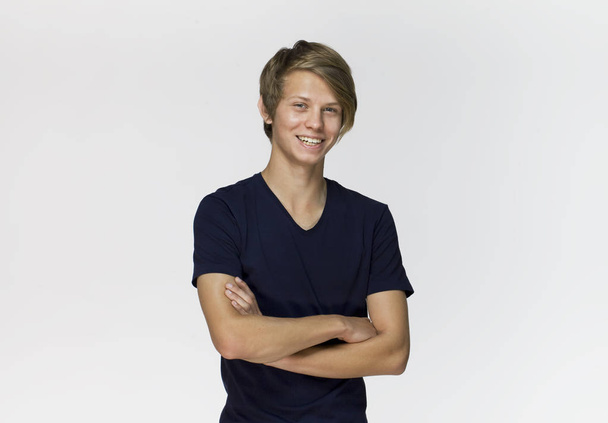 Cheerful smiling teenager in blue, black t-shirt with crossed arms against white background studio shot, isolated - Фото, зображення