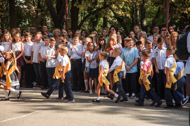 ODESSA, UKRAINE September 1, 2018: September 1, day of the celebration of knowledge. Smiling happy first graders and their happy parents. Teacher in schoolyard holiday Beginning of the training year - Foto, afbeelding