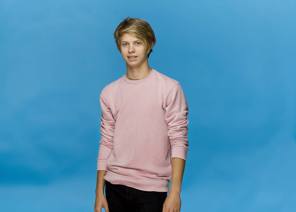 Handsome happy smiling young man wearing pink blouse studio portrait against blue wall - Fotoğraf, Görsel