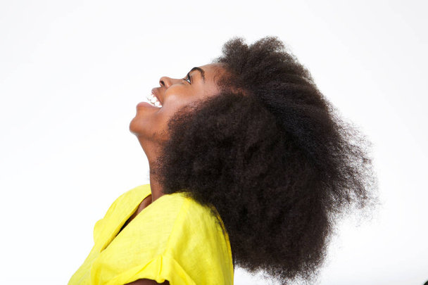 Close up profile portrait of attractive young black woman with afro hair laughing against isolated white background - Photo, Image