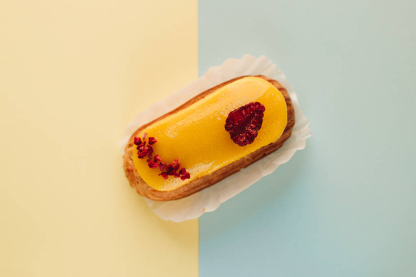 смачний еклер з жовтою глазур'ю, солодкий десерт
  - Фото, зображення