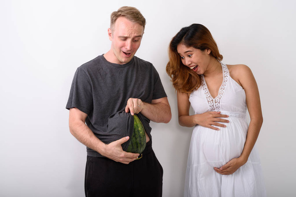 Homme tenant son estomac comme s'il serait enceinte de pastèque tout en riant femme
 - Photo, image