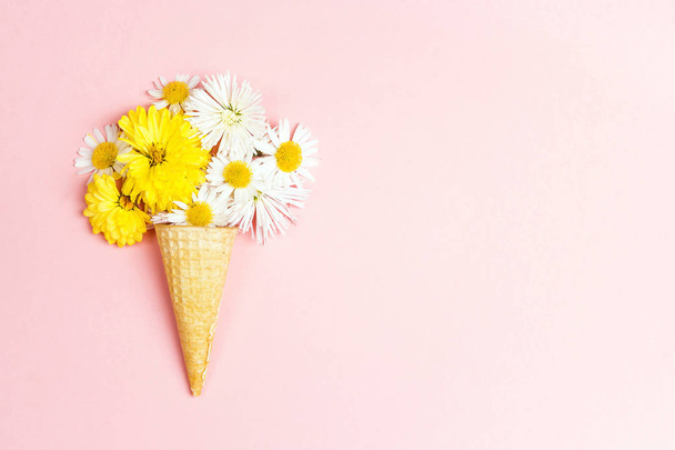 Waffle cone with flowers on pink background and copy space. Flat lay, top view. - Фото, зображення