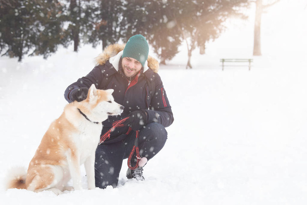 Akita dog with its owner in snowy day. Winter concept - Foto, immagini