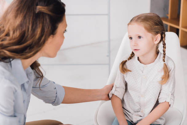 close-up shot of adult psychologist talking with little patient in office - Photo, Image