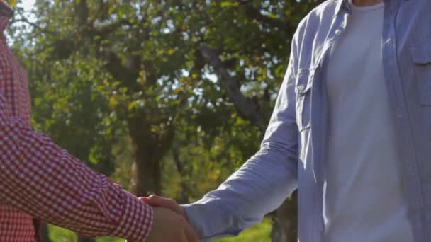 Deux agriculteurs méconnaissables se serrent la main sur un fond d'arbres verts
 - Séquence, vidéo