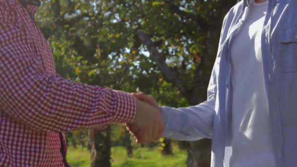 Zwei nicht wiedererkennbare Bauern schütteln Hände und bereiten sich auf den Abschluss eines Abkommens über grüne Bäume vor - Filmmaterial, Video