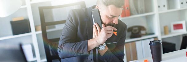 Bir adam ofiste masa başında oturan, telefonda konuşurken ve dudaklarını bir marekker holding. - Fotoğraf, Görsel