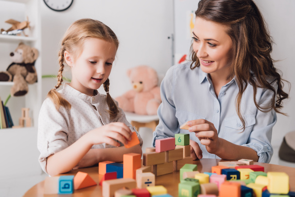 happy mother playing blocks with adorable little child - Photo, Image