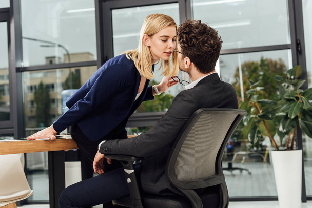 side view of attractive businesswoman flirting with business colleague at workplace in office - Φωτογραφία, εικόνα
