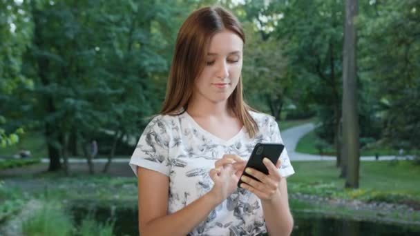 An attractive young lady using a phone in town. Medium shot. Soft focus - Footage, Video