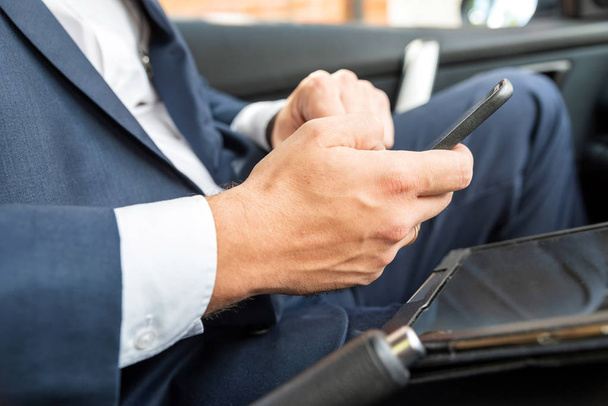 Homme d'affaires travaillant sur tablette et smartphone à l'intérieur de la voiture le jour lumineux
 - Photo, image