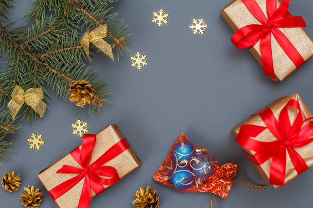 Weihnachtsdekoration. Geschenkboxen, Tannenzweige mit Zapfen auf grauem Hintergrund. Ansicht von oben. Weihnachtsgrußkarten-Konzept. - Foto, Bild