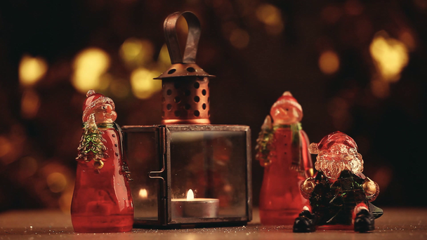 Nieuwjaar speelgoed Santa Claus sneeuwpop figuur wax lamp goud bokeh houten tafel hd beelden  - Video