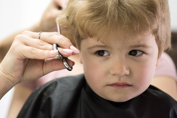Rough fringe cut. Little child given haircut. Small child in hairdressing salon. Little boy with blond hair at hairdresser. Cute boys hairstyle. Hair salon for kids. Just a little off here - Photo, Image