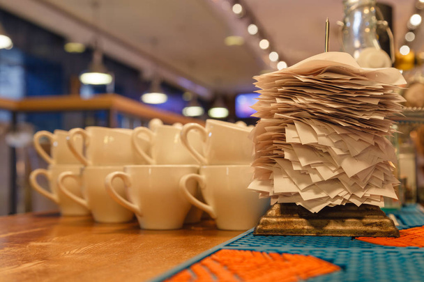 Canecas de cerâmica branca para chá e cheques de encomendas concluídas no bar ou restaurante cozinha empalada em uma agulha de ferro fino afiada em um suporte. Verificador de conceito, suporte para cheques, checkbo
 - Foto, Imagem