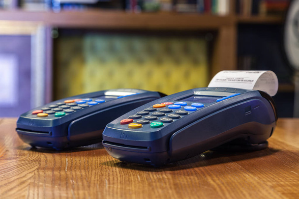 Bankovní terminál s Vytisknutý šek a barevná tlačítka stojící na dřevěný stůl. Koncept placení účtů v restauraci a obchod, nákupy kreditní kartou - Fotografie, Obrázek