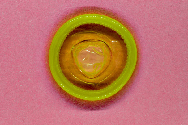 Προφυλακτικό κίτρινο χρώμα ροζ φόντο επιφάνειας - Φωτογραφία, εικόνα