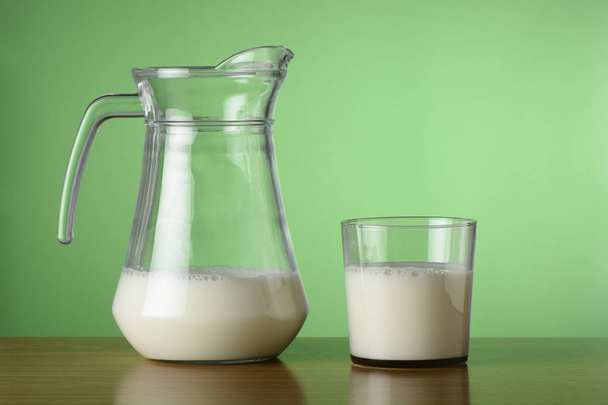 Glass of milk and jar on green background - Foto, immagini