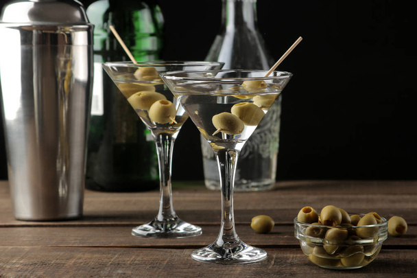 Martini in a glass wineglass with green olives on a skewer on a brown wooden table. cocktails. bar - Foto, Imagen