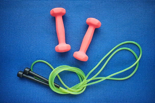 Set of jump rope and dumbeells on the blue background, top view - Photo, Image