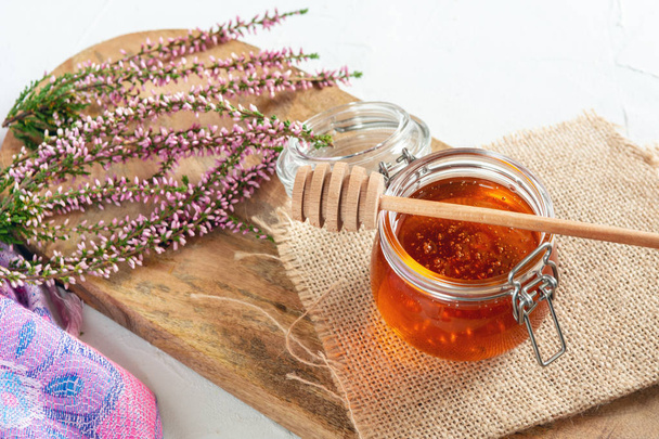 Honing in pot met verse heather op houten achtergrond - Foto, afbeelding
