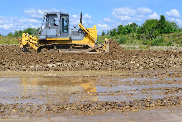 The bulldozer performs works in the tideway of mountain small river - Zdjęcie, obraz